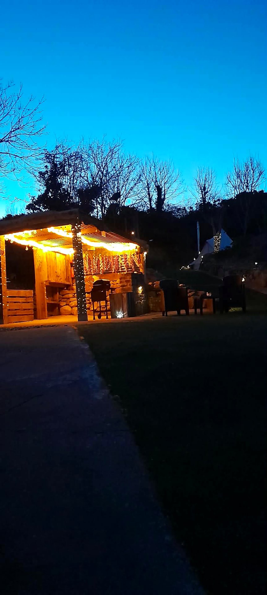 The cooking shelter glowing after dark with the bell tent lit up on the slope behind