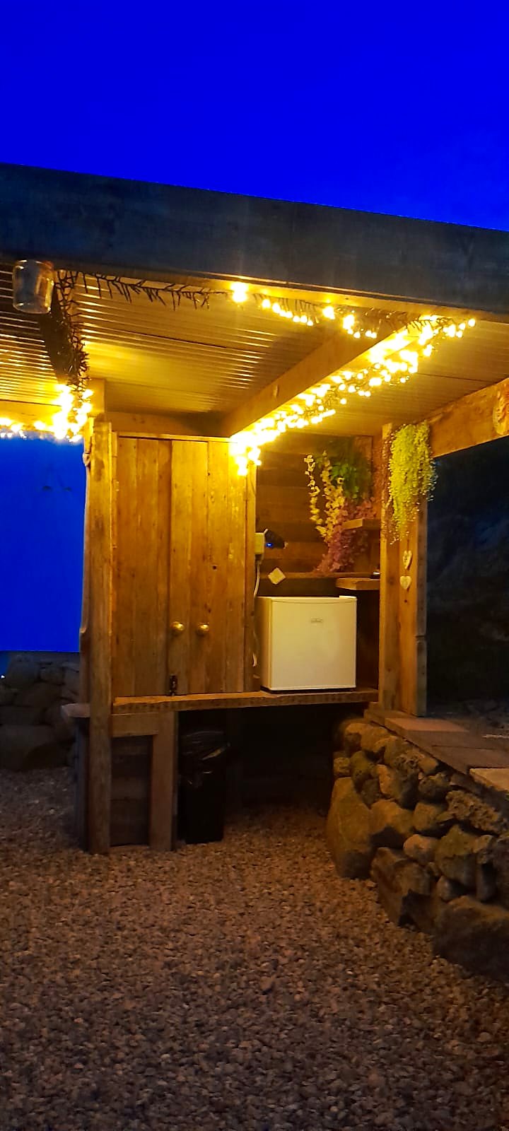 The kitchen corner with fridge under fairy lights at blue hour