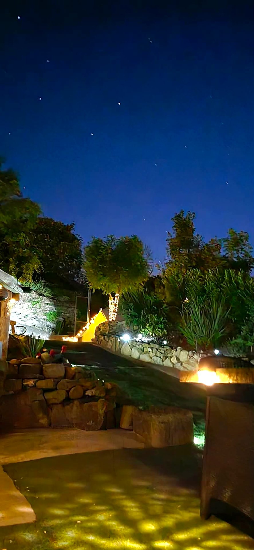 Stars over Fairy Cove at night with lantern light along the stone terraces