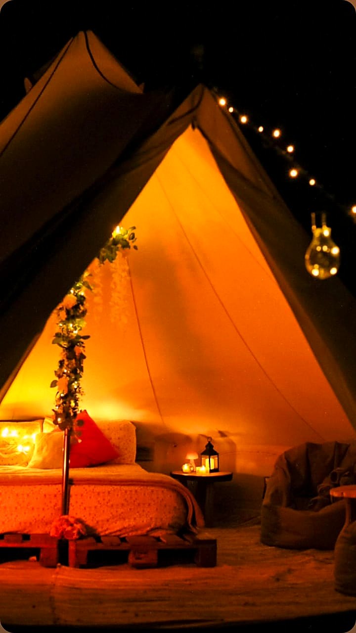 Inside Fairy Fort at night, the bed lit by lanterns and warm string lights
