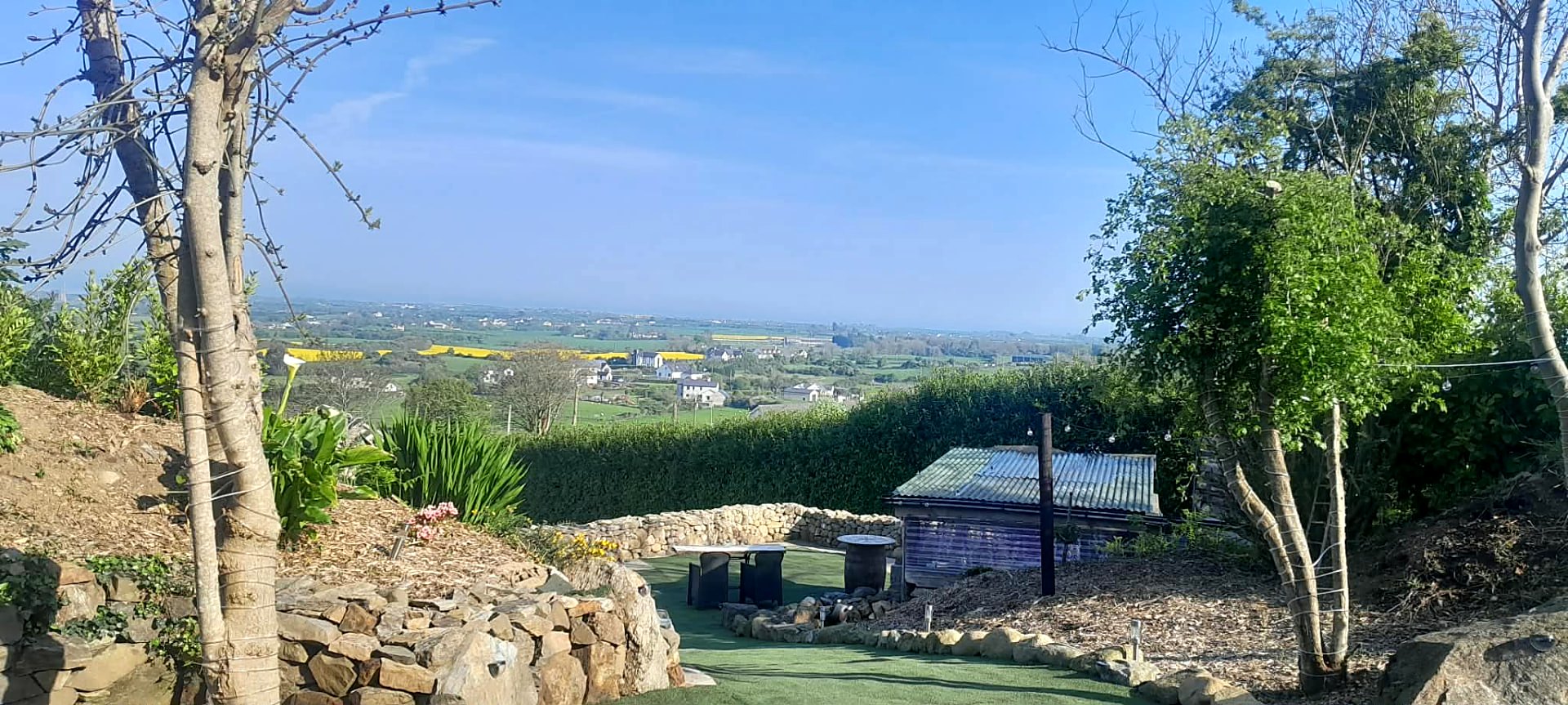 Lawn and dry stone walls at Fairy Cove with the countryside falling away below